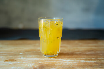 Fresh Look Drink in Yellow Color with Passion Fruit Seeds floating in the glass. Served on the Wooden Table with copy space to input text.