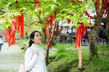 Asian woman make a wish and tie up the ribbon overt the tree