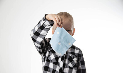 A girl in a checkered shirt holds a handkerchief in her hand against the background of her face....