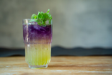 Sweet and Fresh Coctaiol Drink in Purple and Yellow Color isolated with Mint Leaf as Garnish On Top