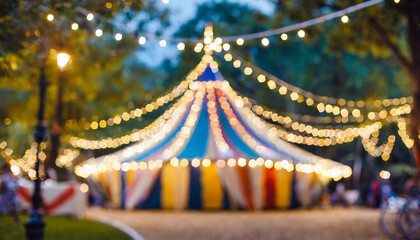 Blurred circus tent with lights garland in night park. Concept of carnival and holidays.