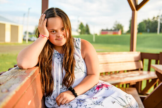 A Portrait of trisomie 21 adult girl outside at sunset