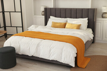 Fototapeta na wymiar Bright plaid on bed in stylish bedroom. Interior design