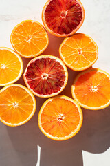 Fresh citrus fruits fool of vitamins: oranges and blood oranges (tarocco) on white background, sunlight, top view, summer vibes, natural  eco concept. Mediterranean diet, close up