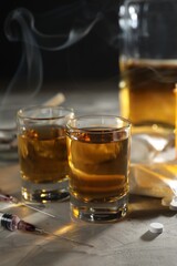 Alcohol and drug addiction. Whiskey in glasses, syringes and pills on grey background