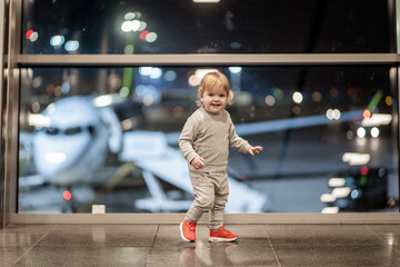 Riga, Latvia - October 19, 2019 - A toddler in a gray outfit and red shoes stands in front of a...