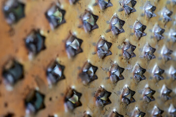 This image presents a detailed close-up view of a metal grater, showcasing the holes designed for...