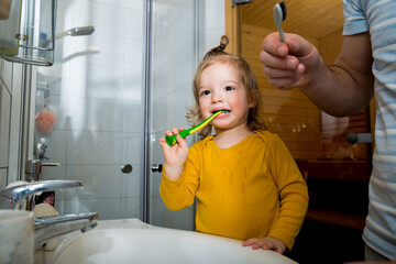 Happy boy and father with toothbrush standing by bathroom sink. Dental health and hygiene for children. Toddler brushing teeth at home. Family life