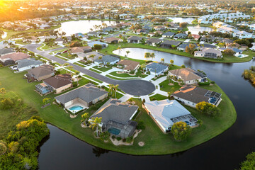 Cul de sac street dead end at sunset and private residential houses in rural suburban sprawl area in North Port, Florida. Upscale suburban homes with large waterfront backyards - obrazy, fototapety, plakaty
