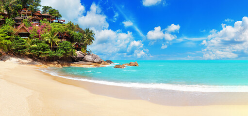 Tropical island paradise sand sea beach, ocean water, palm tree, sun blue sky cloud, villa bungalow on cliff, resort hotel hut houses on rocks, Caribbean, Maldives, Thailand, summer holidays, vacation