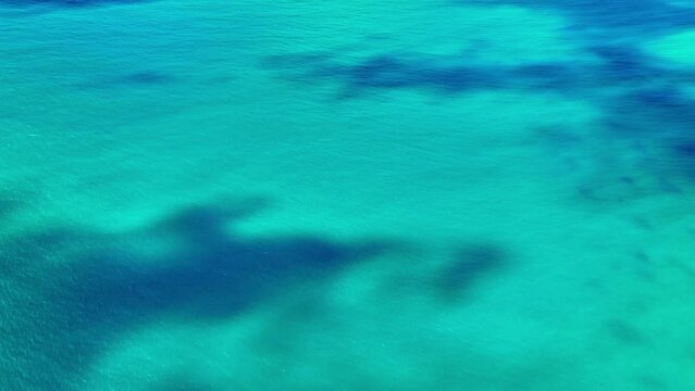 Blue surface with waves of the Atlantic Ocean. Aerial view of the sea surface. Abstract background of water flow under the influence of light. Turquoise wavy background. Texture of water or liquid.