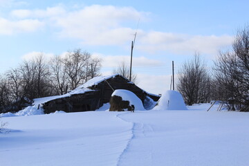 Fototapeta premium two haystacks stand near an old house in early spring on a sunny winter day
