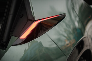 The right rear light shining on a new modern electric sedan car. The concept of the future. Red...