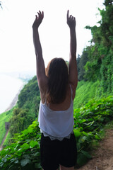 woman hands up back view in the rainforest. women power, success and happiness concept, women's day holidays