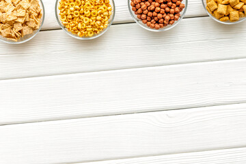 cereals, oatflakes and cornflakes for healthy breakfast on white wooden background top view mock up