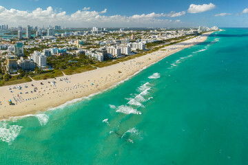 Travel destination in United States. South Beach sandy surface with tourists relaxing on hot Florida sun. Tourism infrastructure in southern USA. Miami Beach city with high luxury hotels and condos
