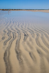 Patterns in the brown sand from wind and waves.  Riffles in the sand with shadowing from late afternoon sun. Brown coarse sand on the Atlantic Ocean.  