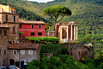Fototapeta na wymiar View of the remains of the Tempio di Vesta (Temple of the Sybil) against a background of green hills in the city of Tivoli, near Rome, Italy