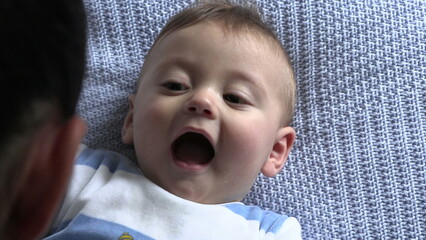 Mother interacting with baby infant. Expressive close-up of toddler face smiling