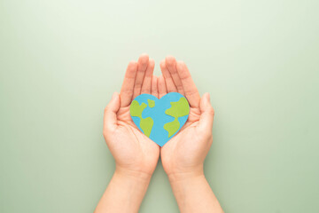 World heart day. Flat lay of hands holding heart shape with earth map made by paper on green...