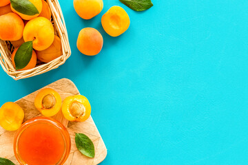 Healthy breakfast. Apricot jam in jar near fresh fruits on blue background top view frame copy space