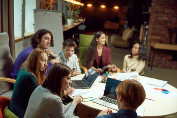 Group of young people, student siting in library, studying together, doing projects together and preparing for exam. Concept of education, youth, knowledge, homework, exams, projects.