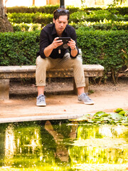 Thirty year old man looking at mobile phone horizontally in a park - 768920230