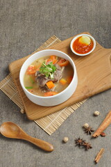 Bowl of meat soup on a wooden table