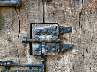 Closeup of an old vintage iron door latch on a very aged wooden door