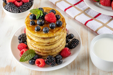 Delicious pancakes with fresh berries on white wooden table. Food concept.