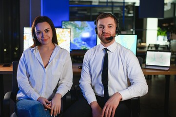Center of dispatching maintenance. Portrait of cheerful woman and man working via headset...