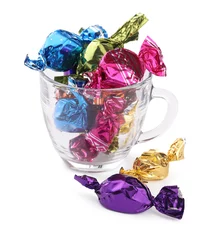 Foto op Plexiglas Glass cup with candies in colorful wrappers isolated on white © New Africa