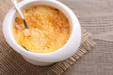 Delicious creme brulee in bowl served on wooden table, closeup