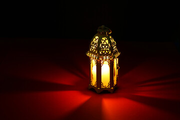 Decorative Arabic lantern on table against dark background. Space for text