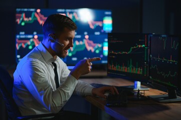 Side view of crypto broker sitting at office table, analyzing market, looking at screen