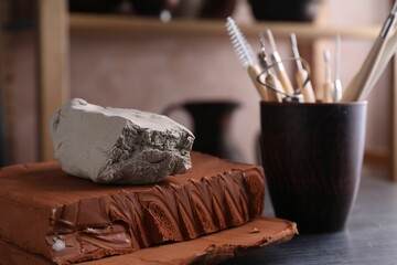 Clay and set of modeling tools on dark gray table in workshop, closeup