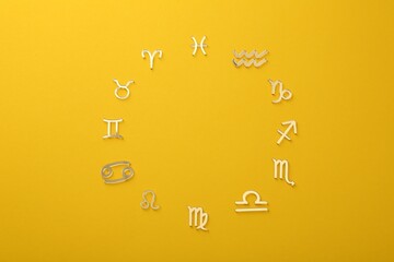 Zodiac signs on yellow background, flat lay. Space for text
