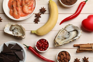 Natural aphrodisiac. Different food products and red decorative heart on light wooden table, flat...