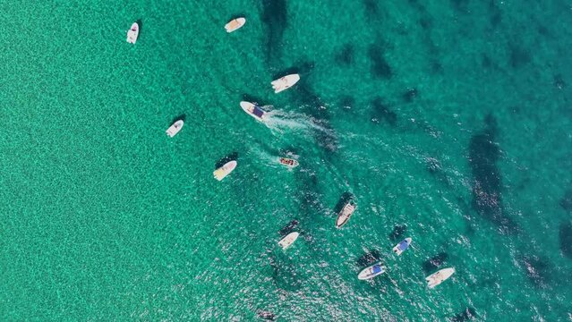 Top down shot - Small tourist boats docked in a bay of turquoise water, boats driving in between the rows trying to find a place.