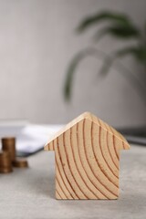 Fototapeta na wymiar Wooden house model on grey table, closeup. Financial savings