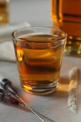 Alcohol and drug addiction. Whiskey in glass, syringes and cocaine on white table, closeup