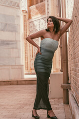 Fototapeta premium A woman in a dress is posing for a photo in front of a brick wall