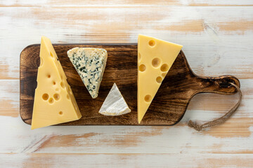 Assortment of different cheese types on white wooden table. Cheese background.