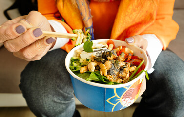 Woman eating poke of fresh asian-inspired salad bowl