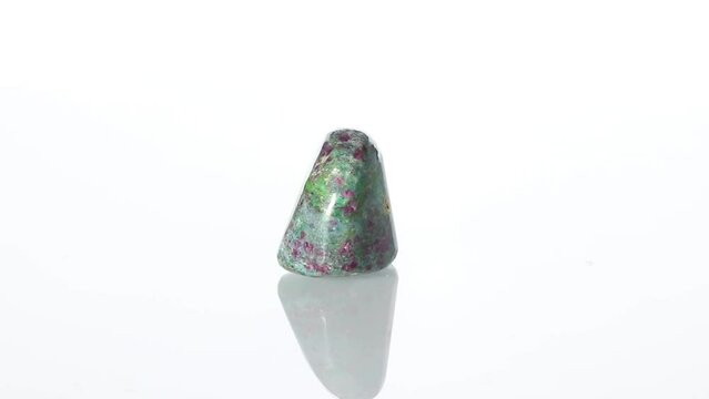 Polished mineral stone Ruby in zoisite rotates in a circle on a white background close-up