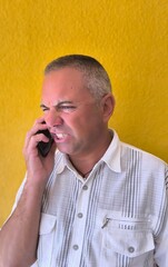 Adult man talking on the phone, with a decidedly irritated face and gritting his teeth with a grimace. Man with personal problems. Heated discussion. Telephone dispute