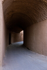 Roofed alley among mud brick houses in ancient city of Yazd, Iran with natural lighting and beautiful details.