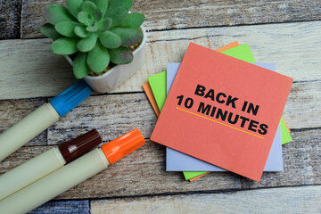 Concept of Back in 10 Minutes write on sticky notes isolated on Wooden Table.
