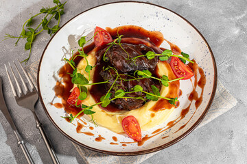 Mashed potatoes with beef in sweet and sour sauce, decorated with tomatoes and microgreens.