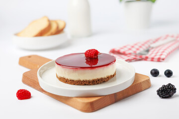 Cheesecake with raspberries on a white plate on a white background